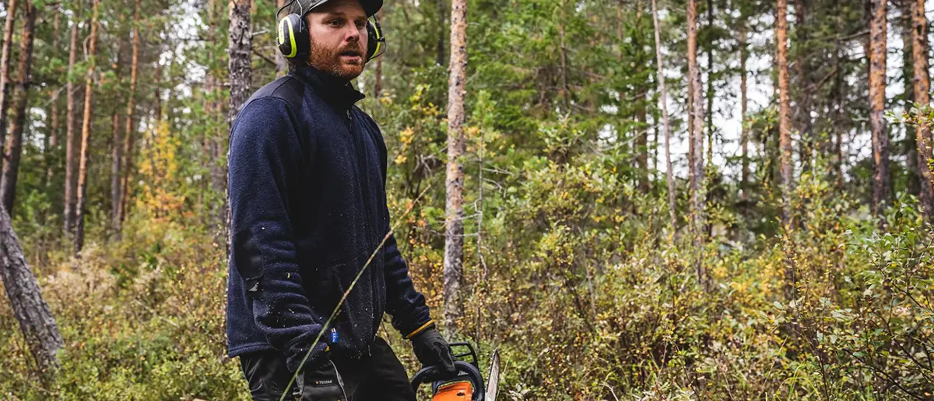 En man står redo med en motorsåg i skogen. Sommar. Foto: CJ Utsi