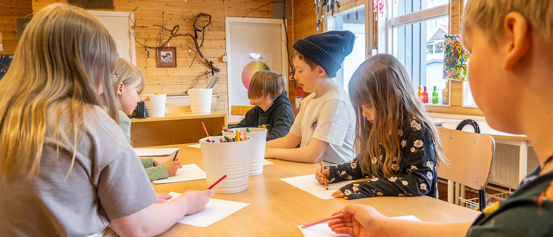 Barn på Västra skolan sitter och ritar vid ett bord.