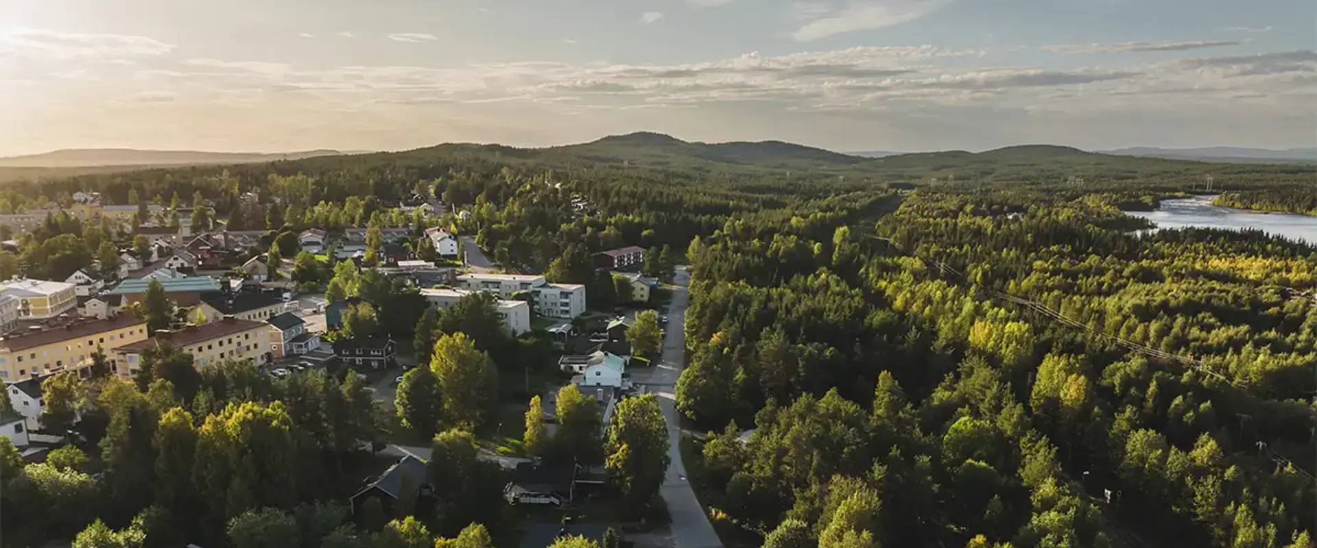 Jokkmokks samhälle med omnejd fotad uppifrån sommartid. Bilden visar både hus, skog och berg. Foto: CJ Utsi