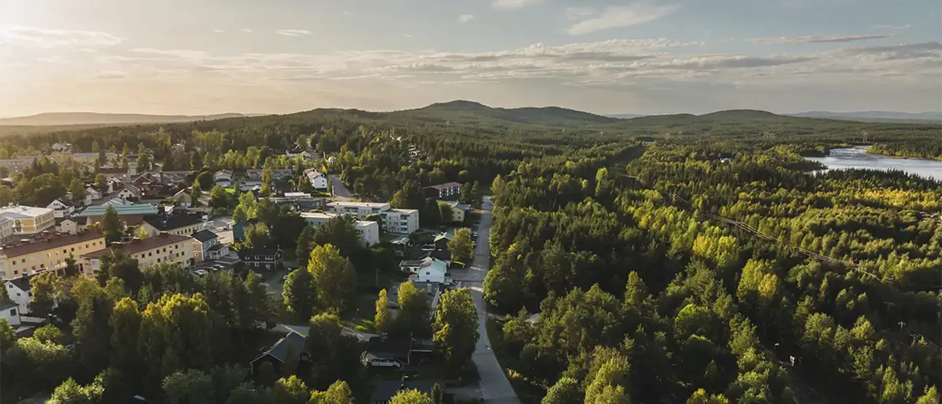 Jokkmokks samhälle med omnejd fotad uppifrån sommartid. Bilden visar både hus, skog och berg. Foto: CJ Utsi